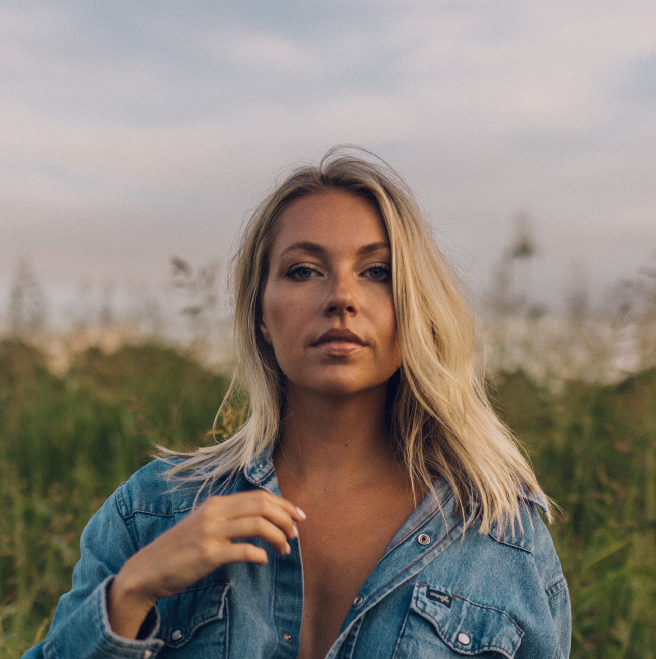 Claudia Hoyser in a denim shirt in a golden field at dusk